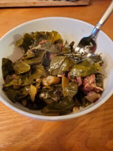 Bowl filled with cooked collard greens and smoked pork. 