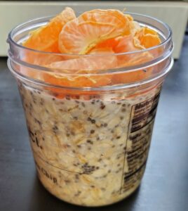 Orange overnight oats with chia seeds in a Talenti jr, topped with mandarin orange segments. 