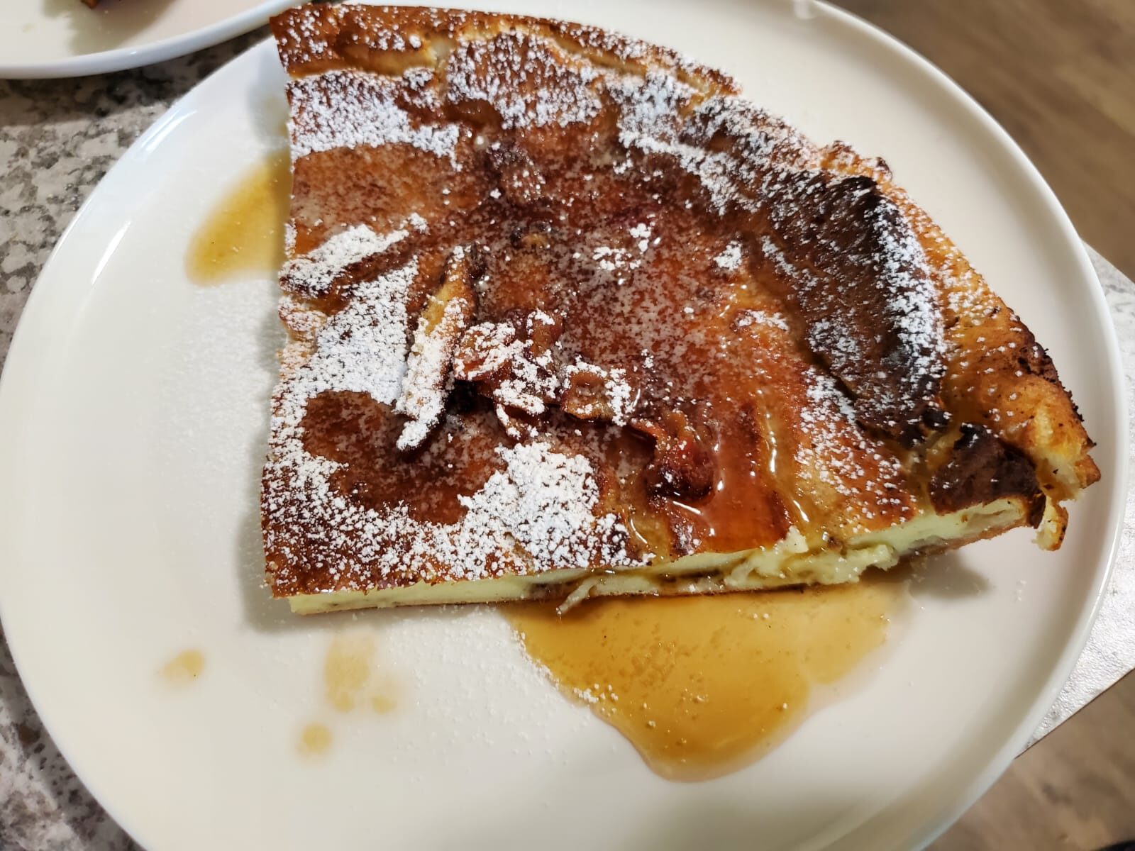 Almost dutch baby dusted with powdered sugar and whiskey bacon maple syrup.