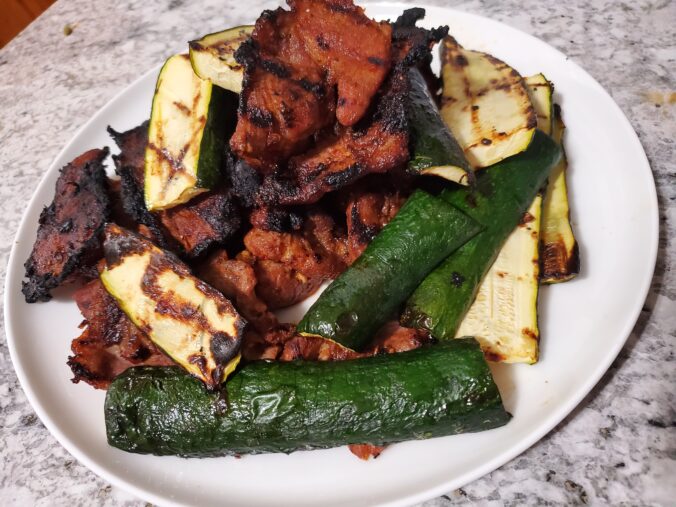 A pile of thinly sliced, slightly charred spicy pork bulgogi mixed in with grilled zucchini.